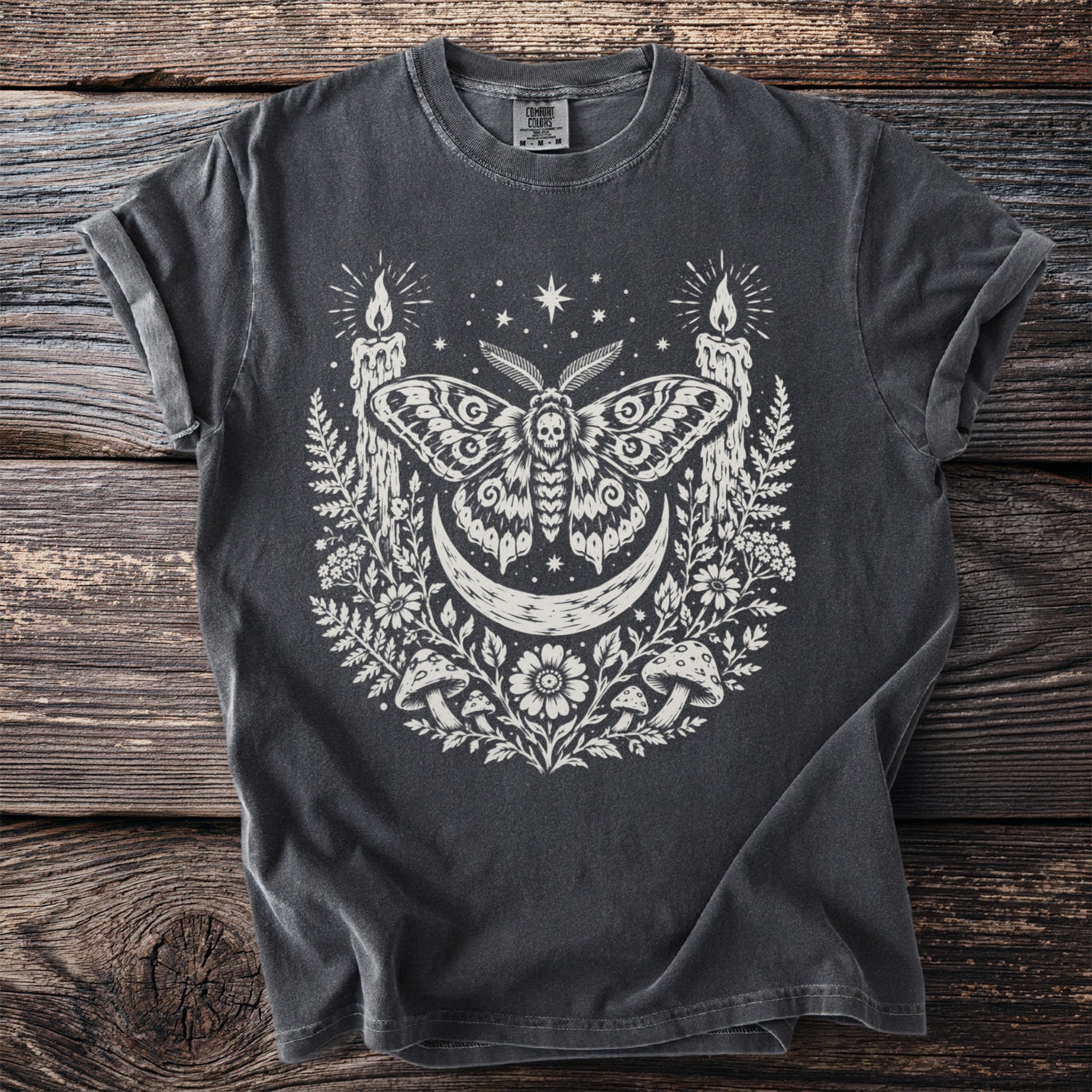 Dark t-shirt with a moth, crescent moon, candles, and floral design.