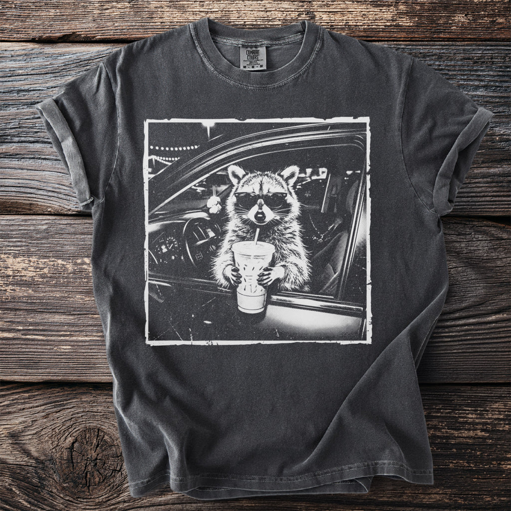 Raccoon wearing sunglasses driving a car and holding a drink.