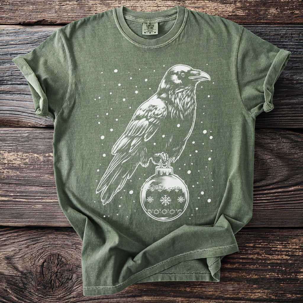 Green t-shirt with white outline of raven perched on a Christmas ornament.