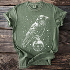 Green t-shirt with white outline of raven perched on a Christmas ornament.