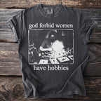 Dark grey t-shirt with text "god forbid women have hobbies" and a vintage scientific illustration.