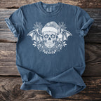Blue t-shirt with white sugar skull wearing Santa hat, bat wings, and holly design.
