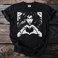 The Morrigan Heart Hands design on a black t-shirt: a feather-haired woman forming a heart with her hands, a raven perched on her wrist.