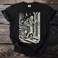Black t-shirt with a cream folk-cut print: Marley's ghost stands at a door in the snow, wrapped in chains, padlocks and cash boxes.