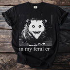 Black t-shirt with a distressed graphic of an opossum and the text "in my feral er."