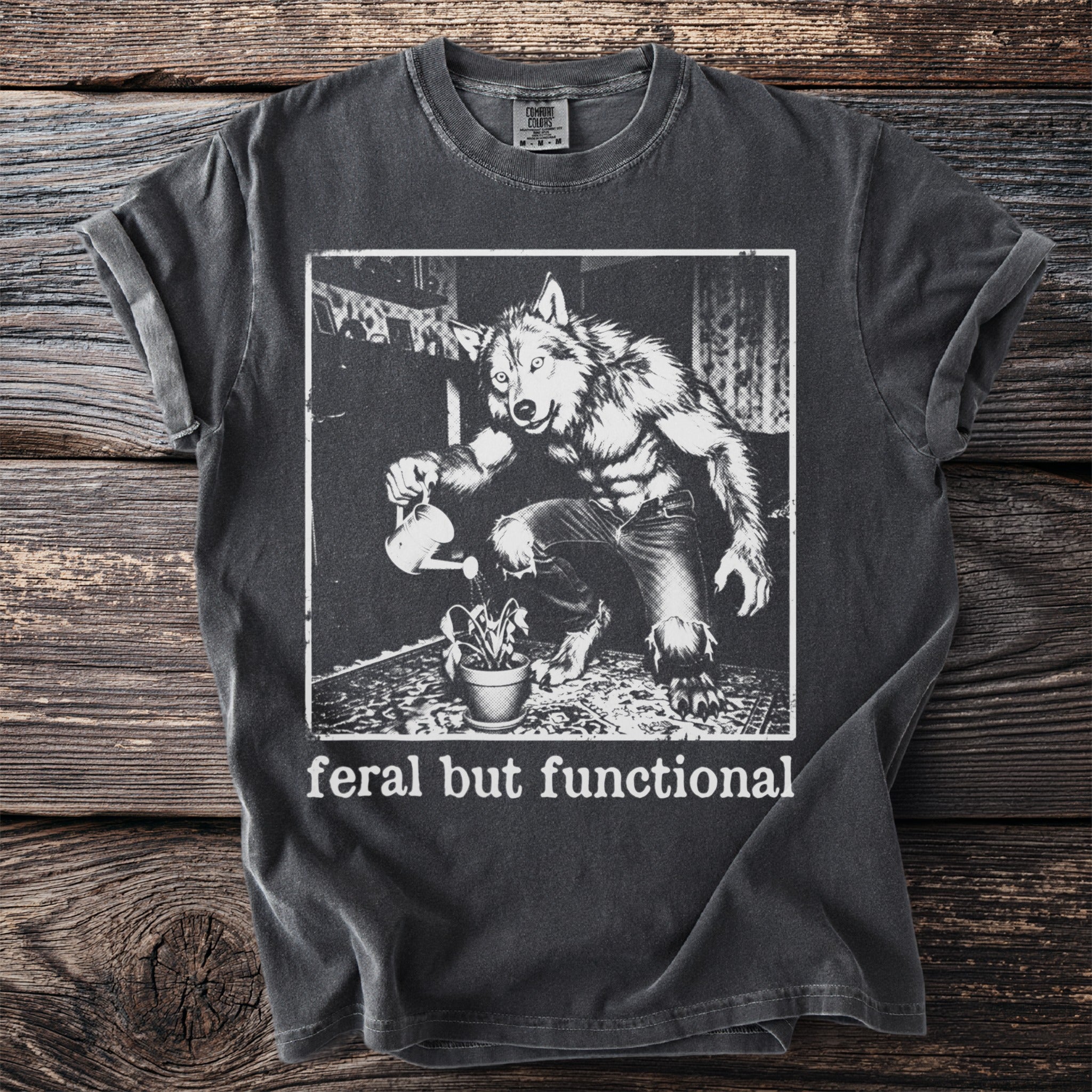 Dark grey t-shirt with werewolf watering plant graphic and "feral but functional" text.