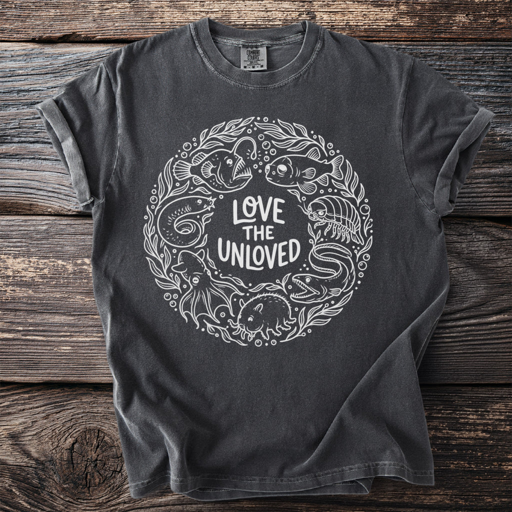Dark gray t-shirt with white line art featuring sea creatures and "LOVE THE UNLOVED" text.