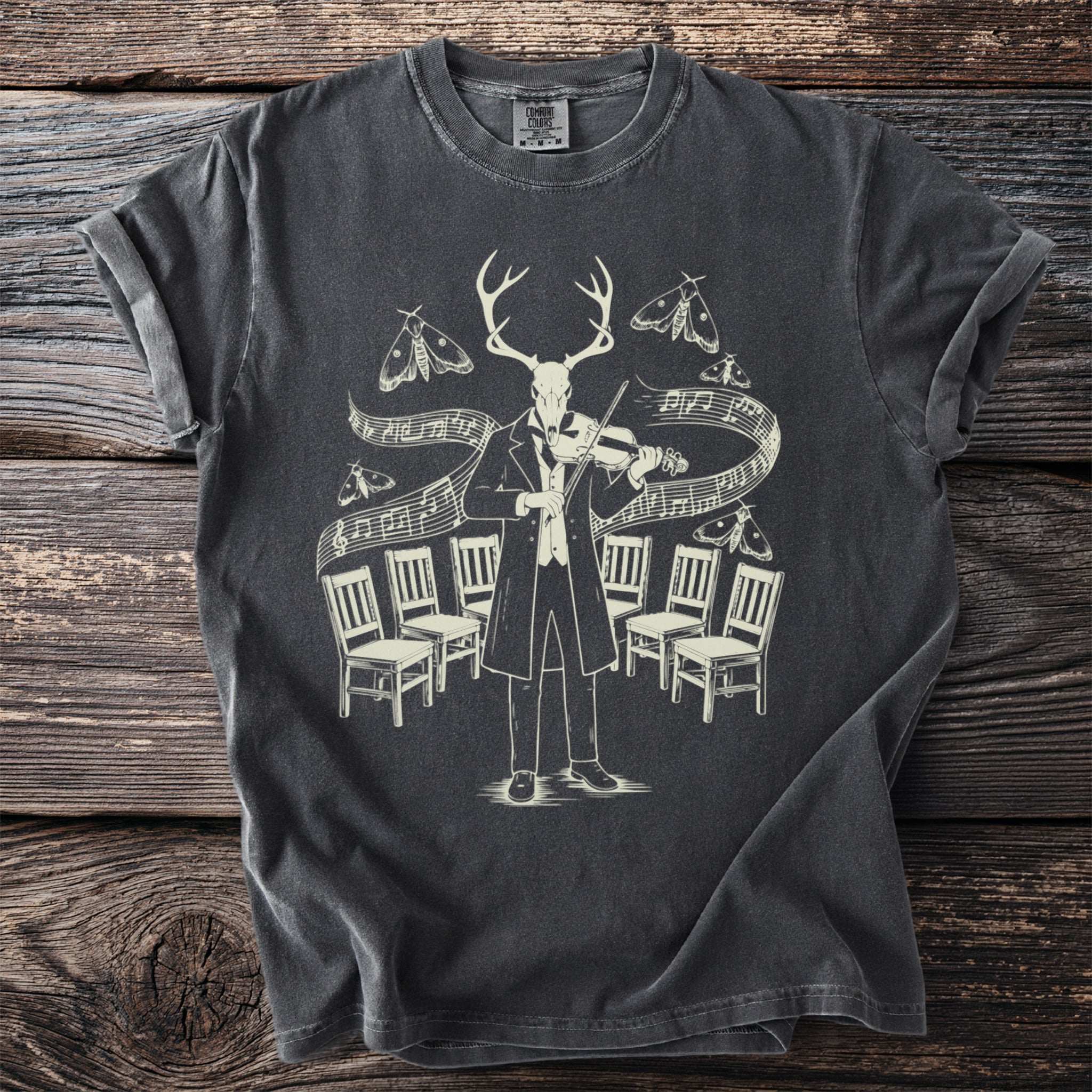T-shirt with graphic of deer skull in tuxedo playing violin surrounded by moths and chairs.