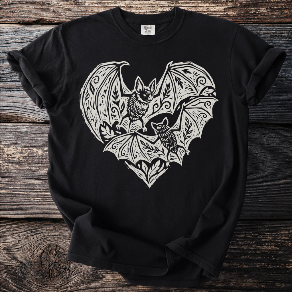 Black t-shirt with a white linocut print of two bats inside a decorative heart shape.