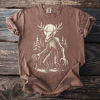 Brown t-shirt with a skeletal creature and moon graphic in a forest.