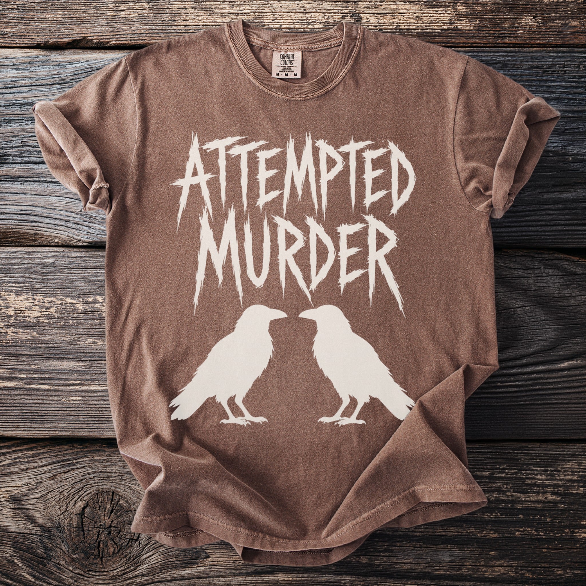 Brown t-shirt with cream "ATTEMPTED MURDER" text and two raven silhouettes.