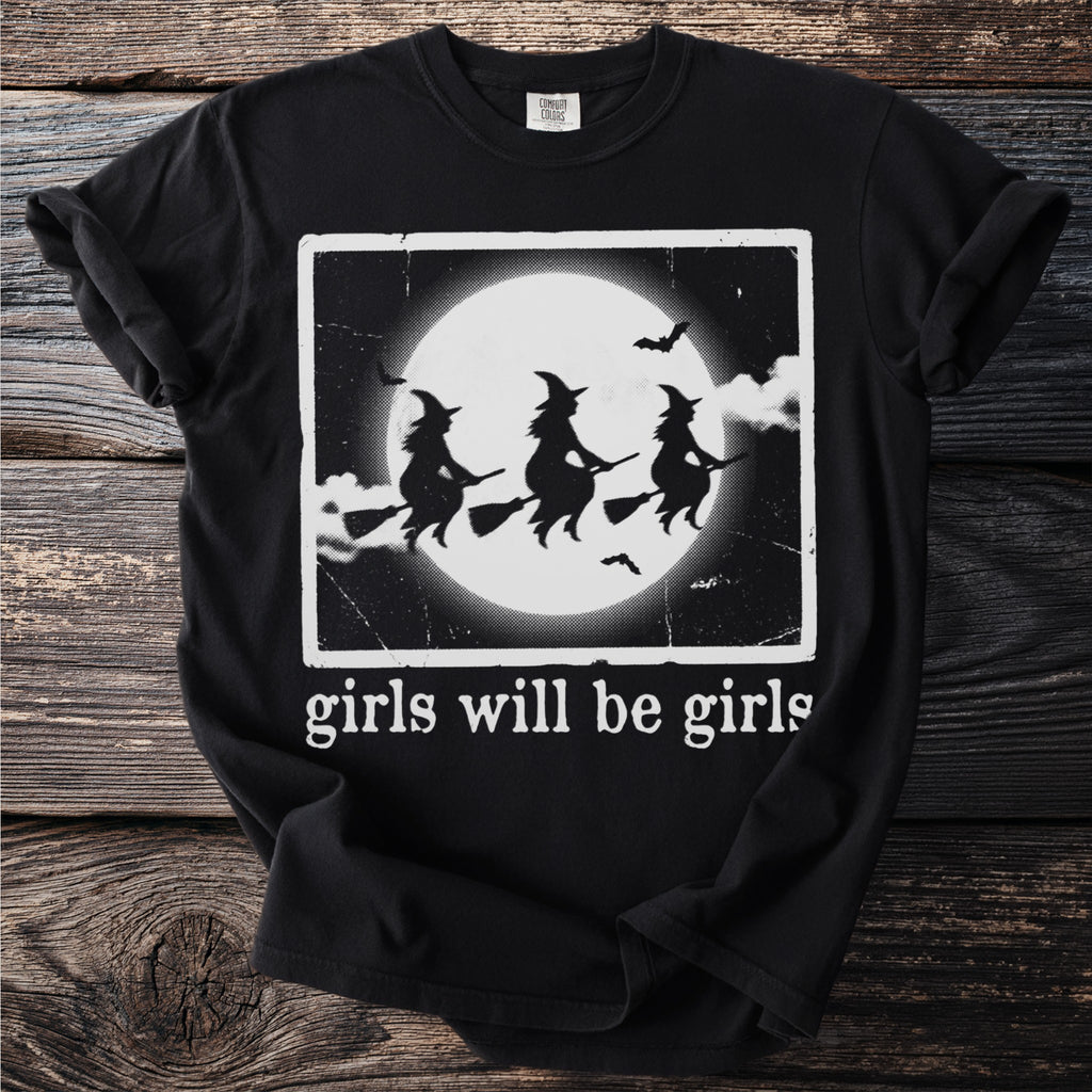 Black t-shirt with graphic of three witches flying on broomsticks in front of a full moon.