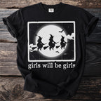 Black t-shirt with graphic of three witches flying on broomsticks in front of a full moon.