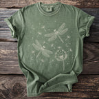Green t-shirt with white graphic of dragonflies, dandelions, moons, and stars