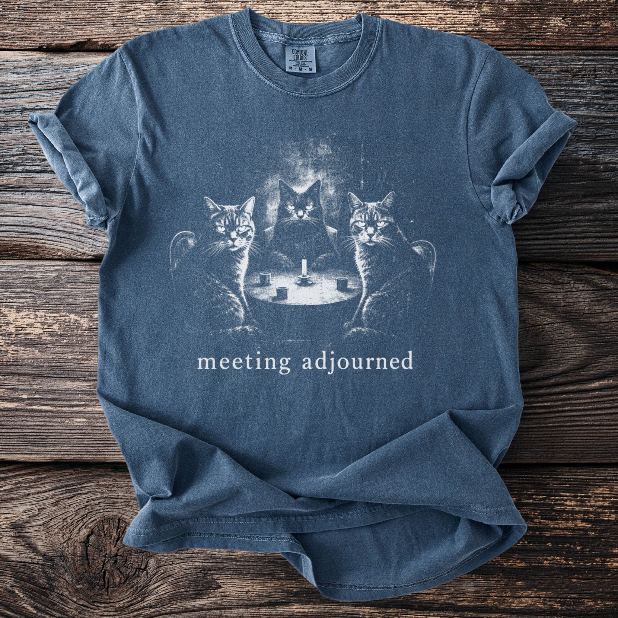 Blue t-shirt with three cats at a table with a candle and text "meeting adjourned".