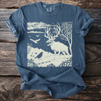 Skeletal stag with crow and birds on a starry night landscape graphic on a blue t-shirt.