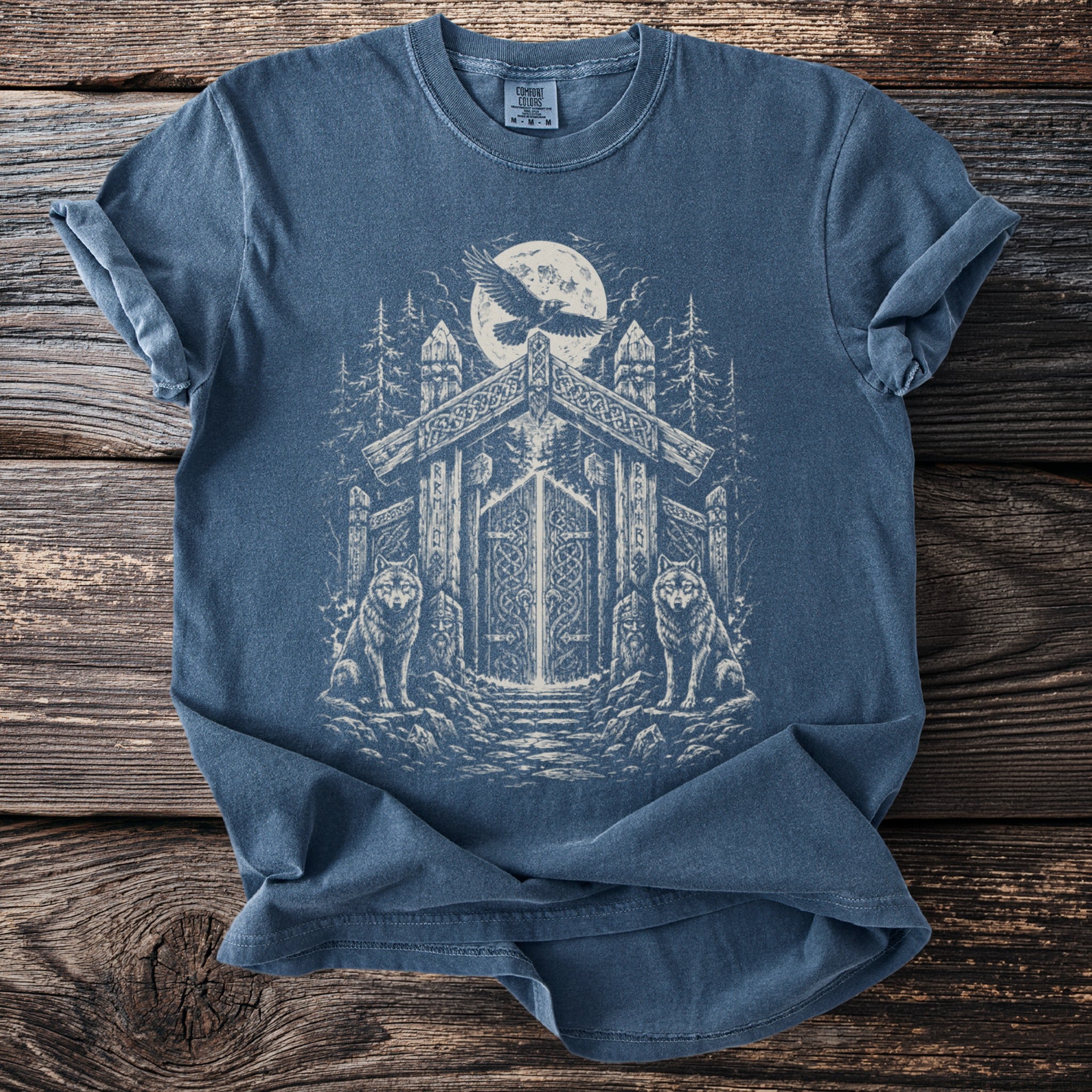 Blue t-shirt with viking-themed graphic of wolves, raven, and ornate gateway under moon.