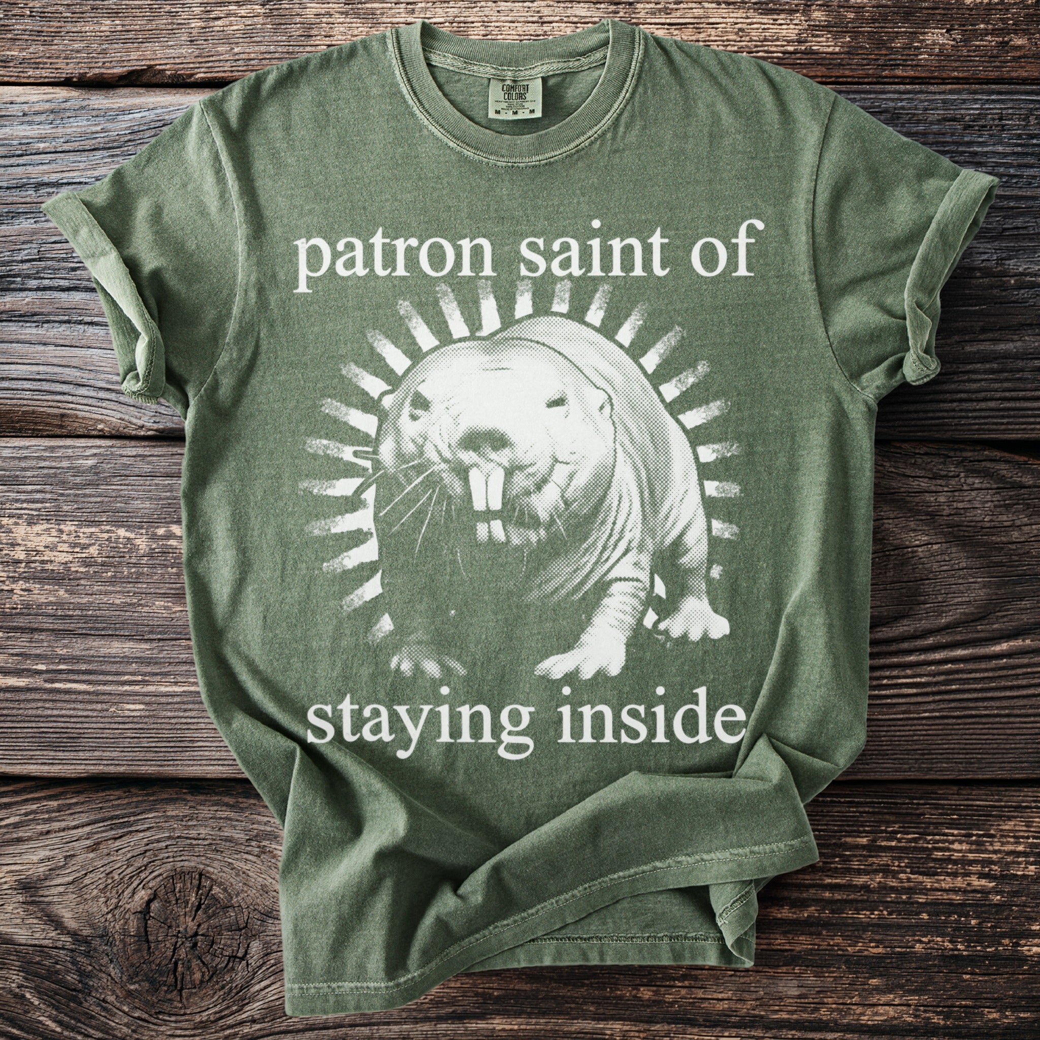 Green t-shirt with graphic of a mole rat and text "patron saint of staying inside."