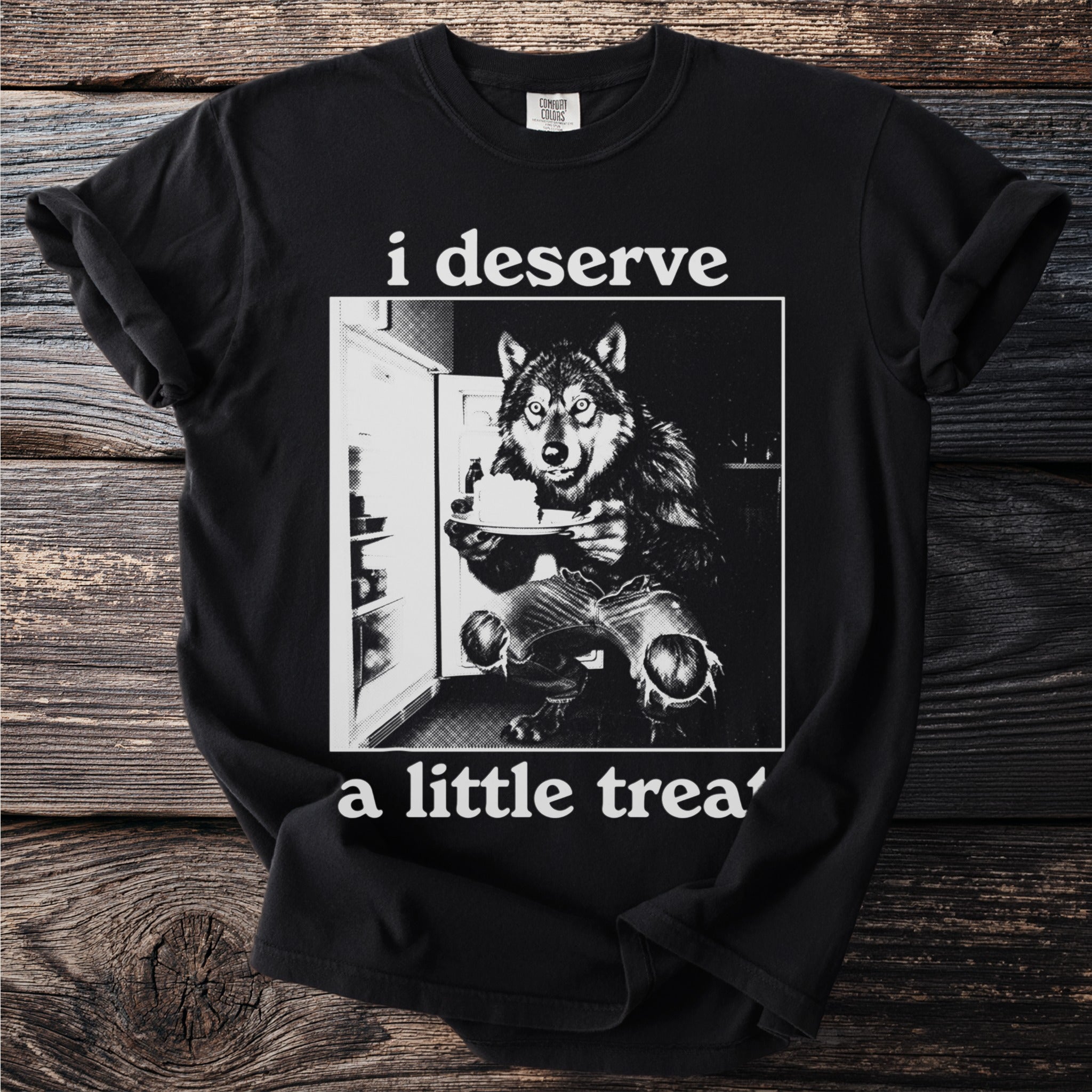 Black t-shirt with a wolf in torn jeans in front of a refrigerator holding cake.