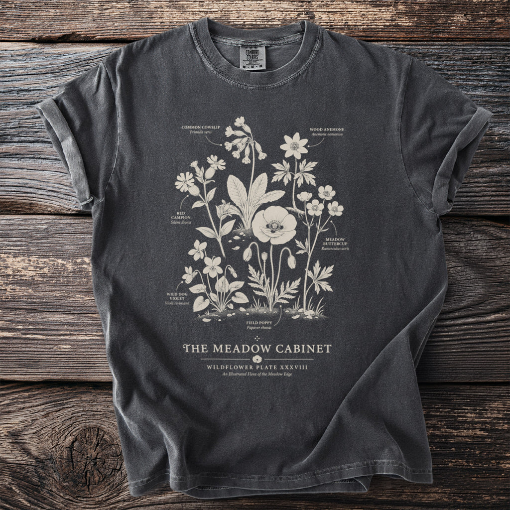 Dark t-shirt with wildflower illustration labeled "The Meadow Cabinet: Wildflower Plate XXXVIII".
