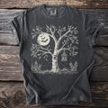 Dark t-shirt with a white linocut design of a tree, moon, bats, and lantern.