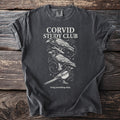 Dark grey t-shirt with "CORVID STUDY CLUB" text and illustrations of birds.