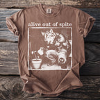 Brown t-shirt with "alive out of spite" and werewolf watering a plant.