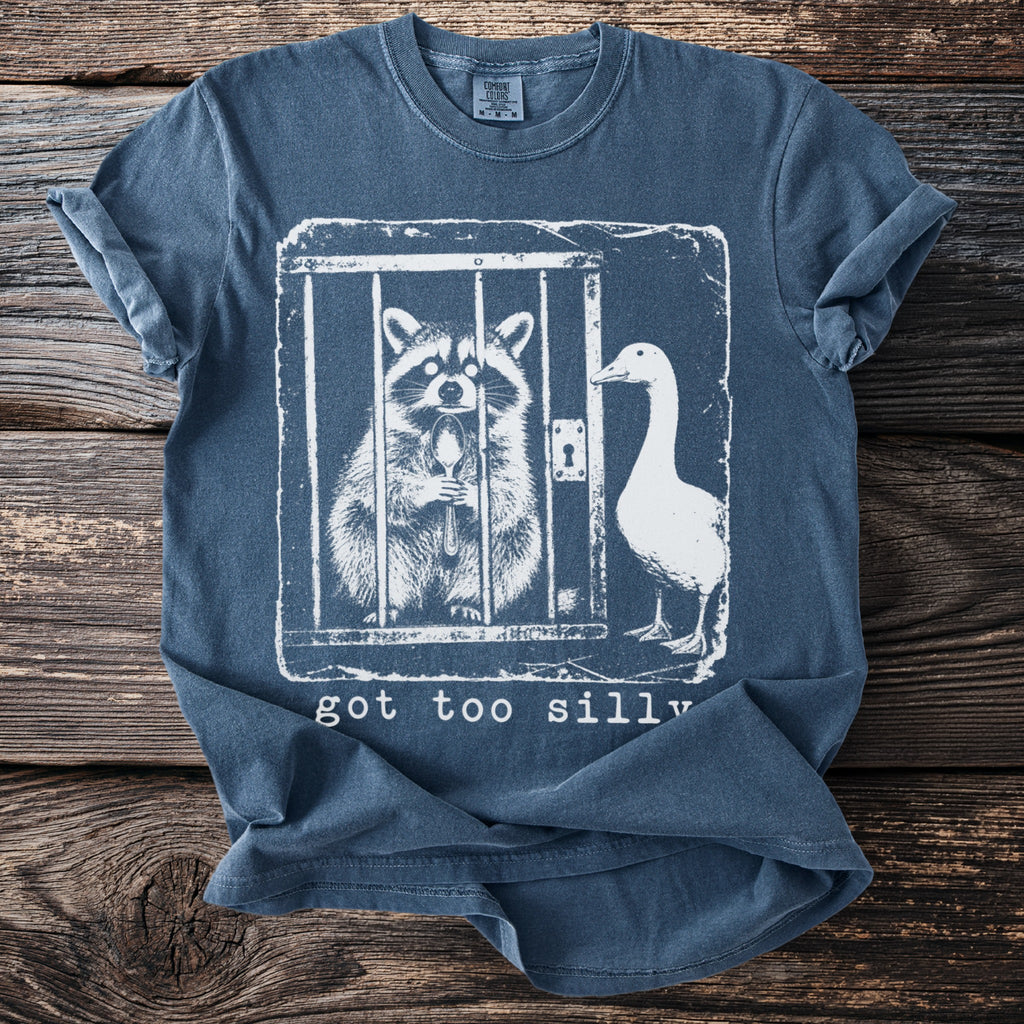 T-shirt graphic with raccoon inside cage holding spoon and duck outside, reads "got too silly".