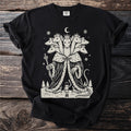 Black t-shirt with a cream folk-cut print: a seven-headed Mouse King in a royal robe and seven crowns faces a small toy soldier in the snow.