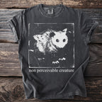 Dark grey t-shirt with a black and white graphic of an opossum and a moth, and text "non perceivable creature".