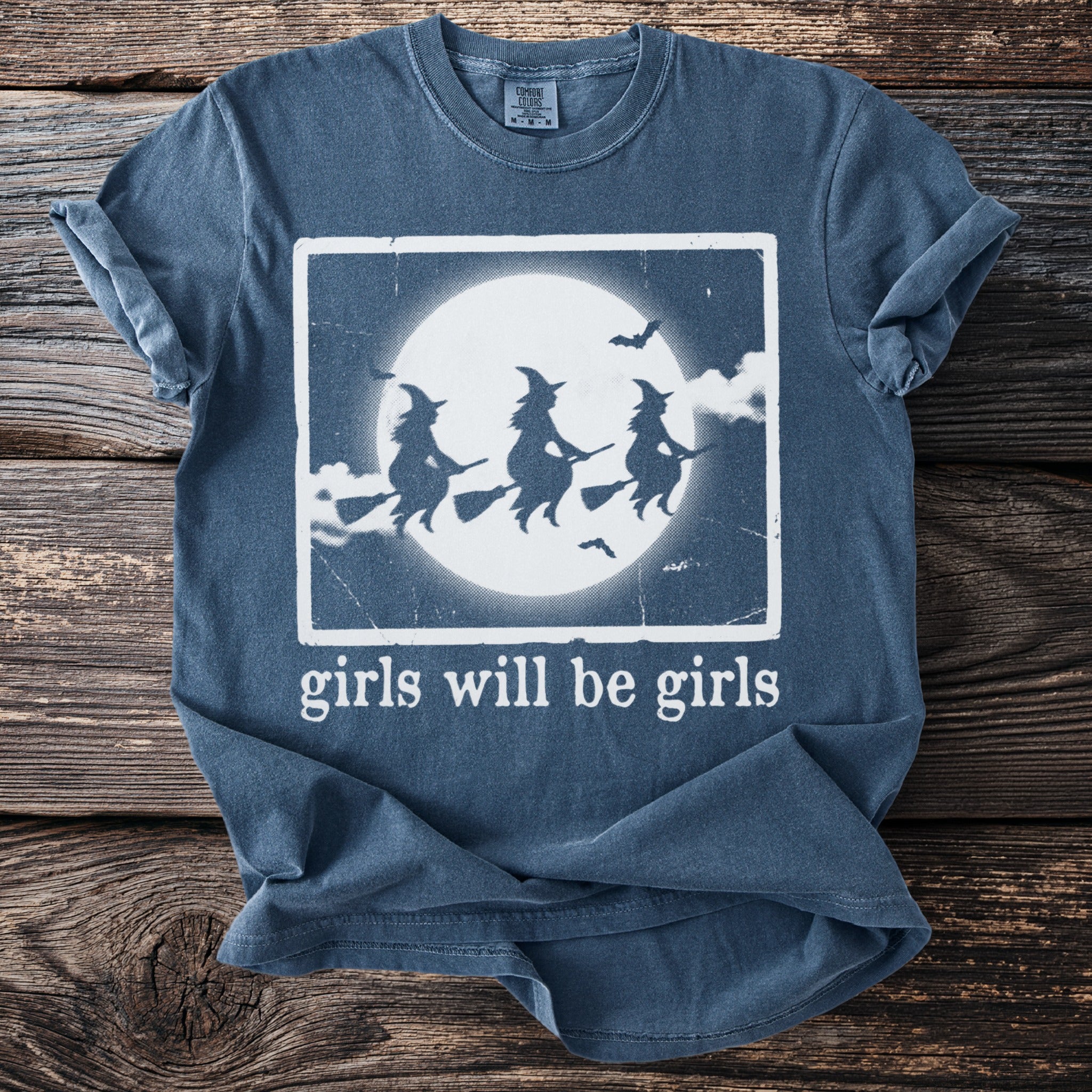 T-shirt with three witches flying on broomsticks in front of a full moon.