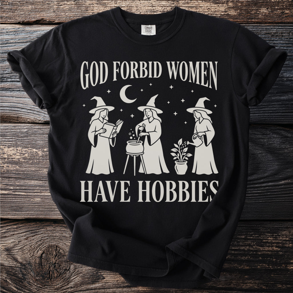 Black t-shirt with white text reading "God forbid women have hobbies" and illustrations.