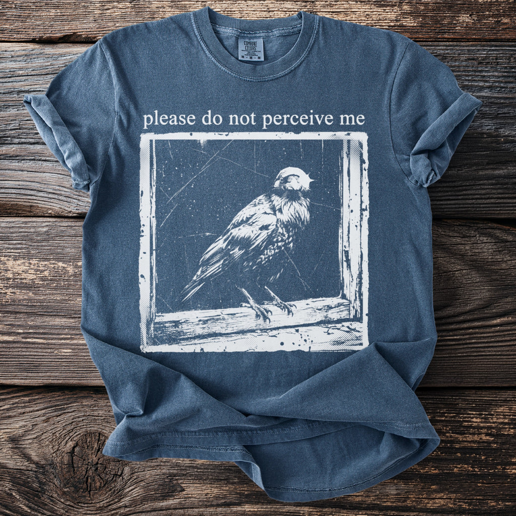 Blue t-shirt with text "please do not perceive me" and a bird graphic.