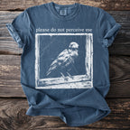 Blue t-shirt with text "please do not perceive me" and a bird graphic.