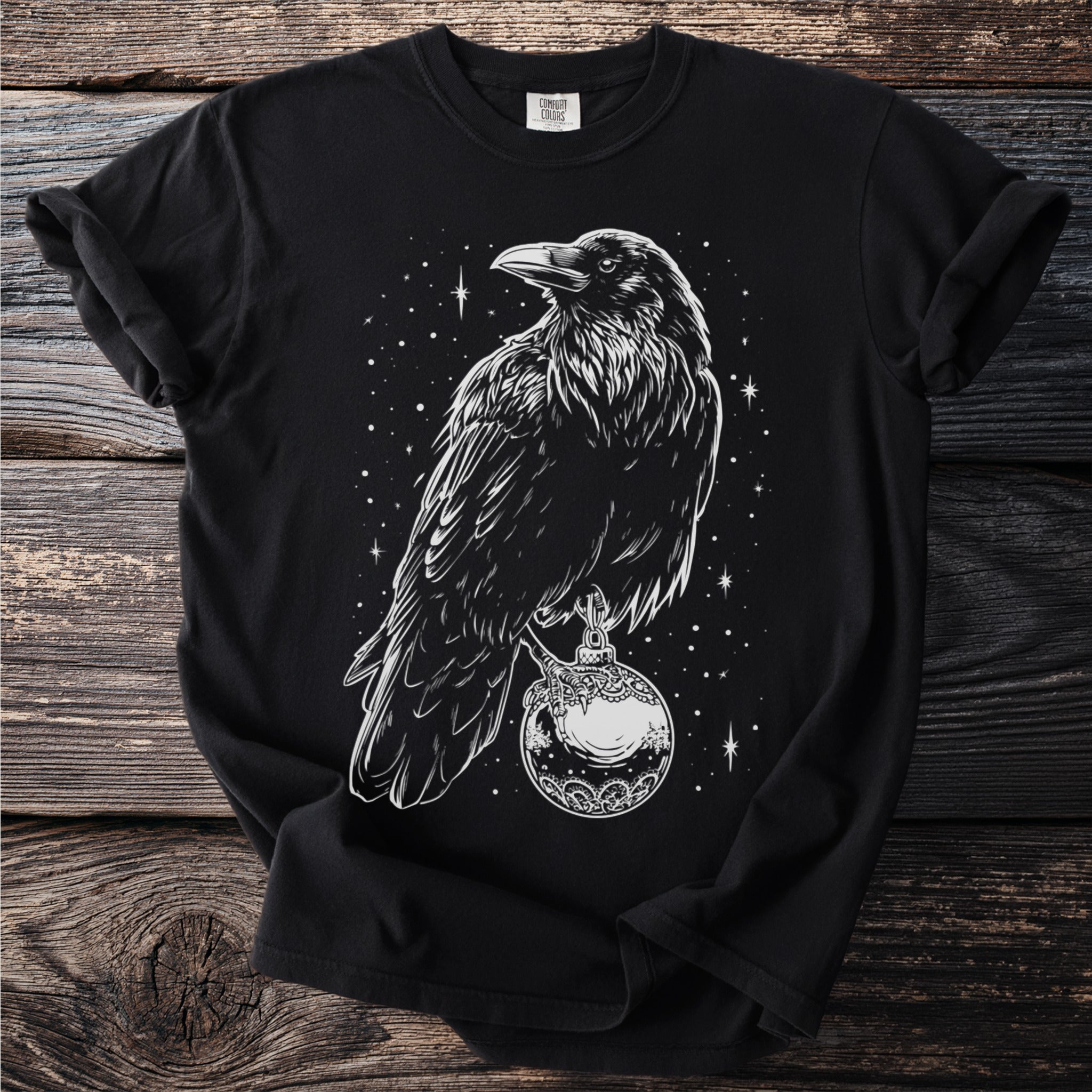 Black t-shirt with white raven perched on ornate ball and starry background.