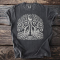 T-shirt with a white print of a tree with roots, moon, house, and well.