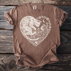 Brown t-shirt with stylized white cats forming a heart, surrounded by flowers and stars.