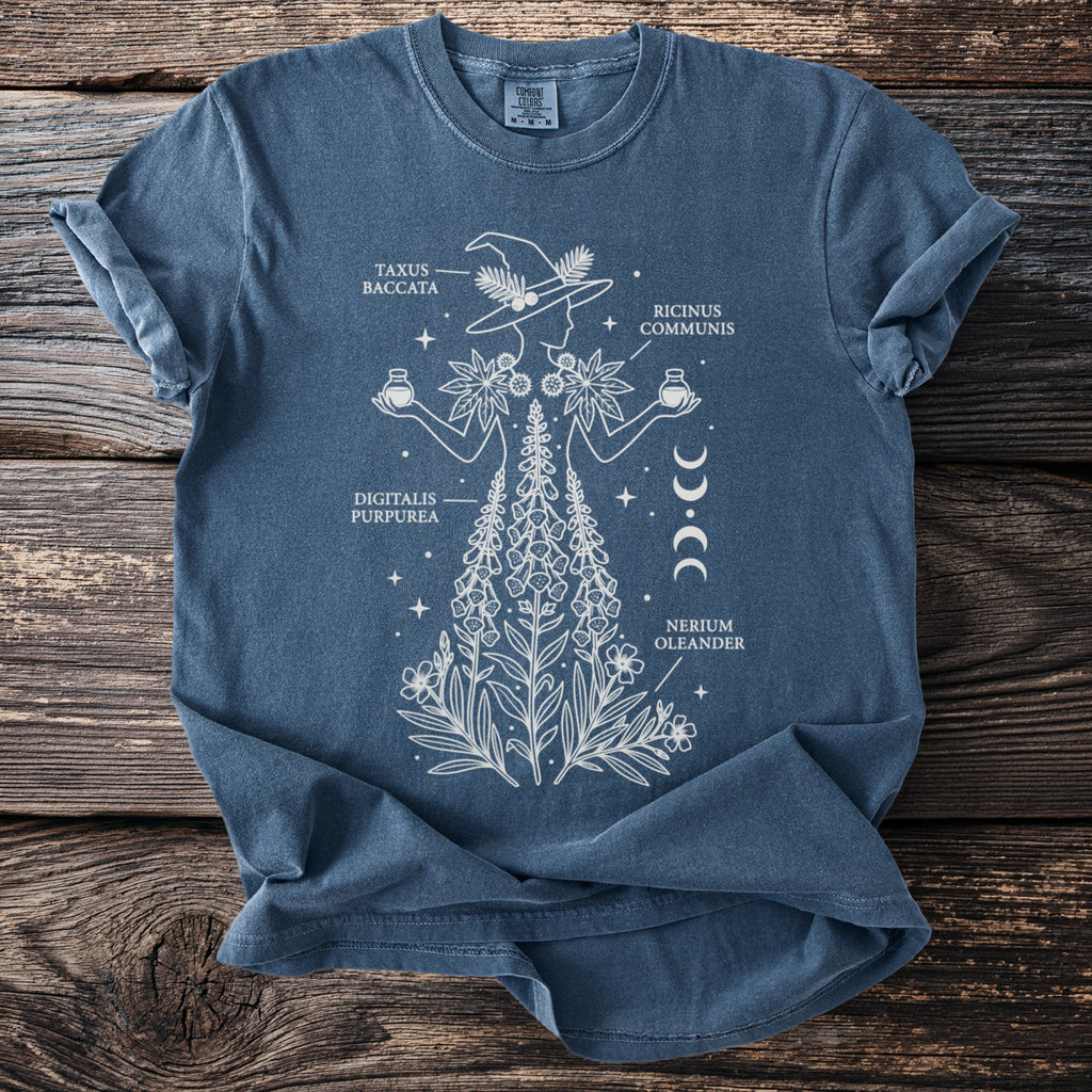 Blue t-shirt with white linework graphic of a witch holding plants and potions.