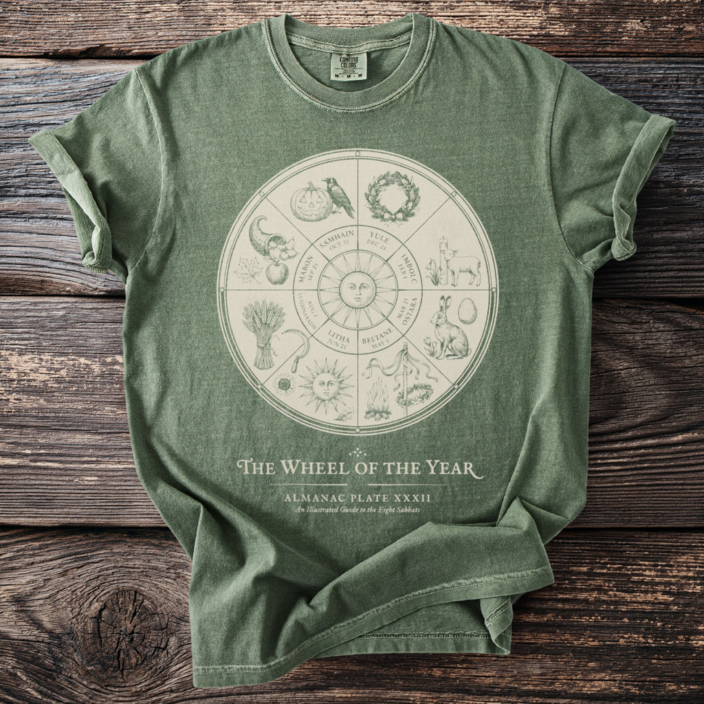 Green t-shirt features "The Wheel of the Year" Almanac illustrated with seasonal symbols.