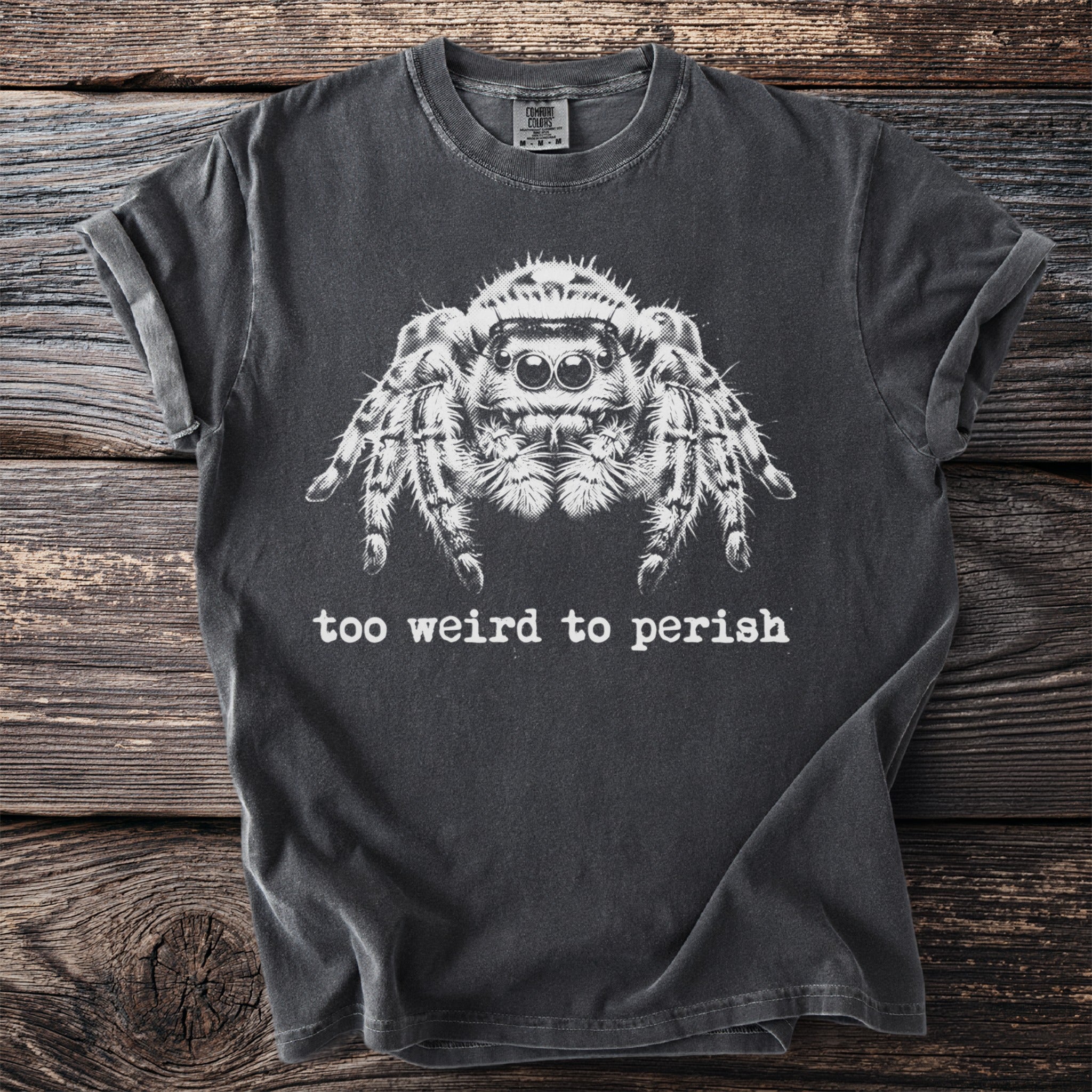 Dark t-shirt with a white jumping spider graphic and the text "too weird to perish".