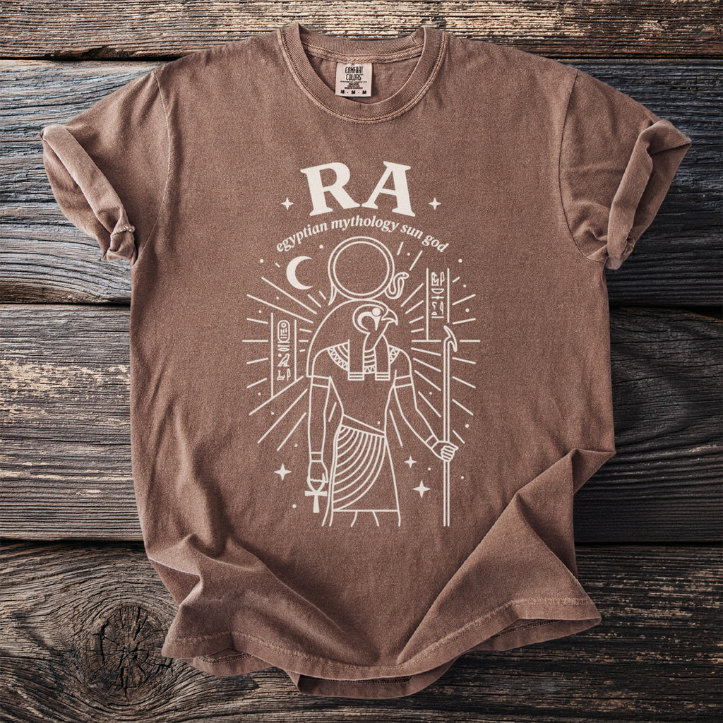 Brown t-shirt with white graphic of Ra, Egyptian sun god, and hieroglyphs.