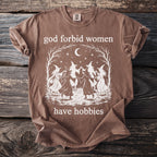 Brown t-shirt with witches dancing and text "god forbid women have hobbies".
